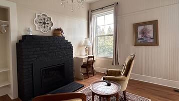 Una sala de estar con chimenea, una araña, una mesa de comedor y un tapete estampado.