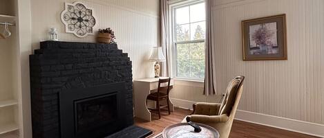 A living room with a fireplace, a chandelier, a dining table, and a patterned rug.