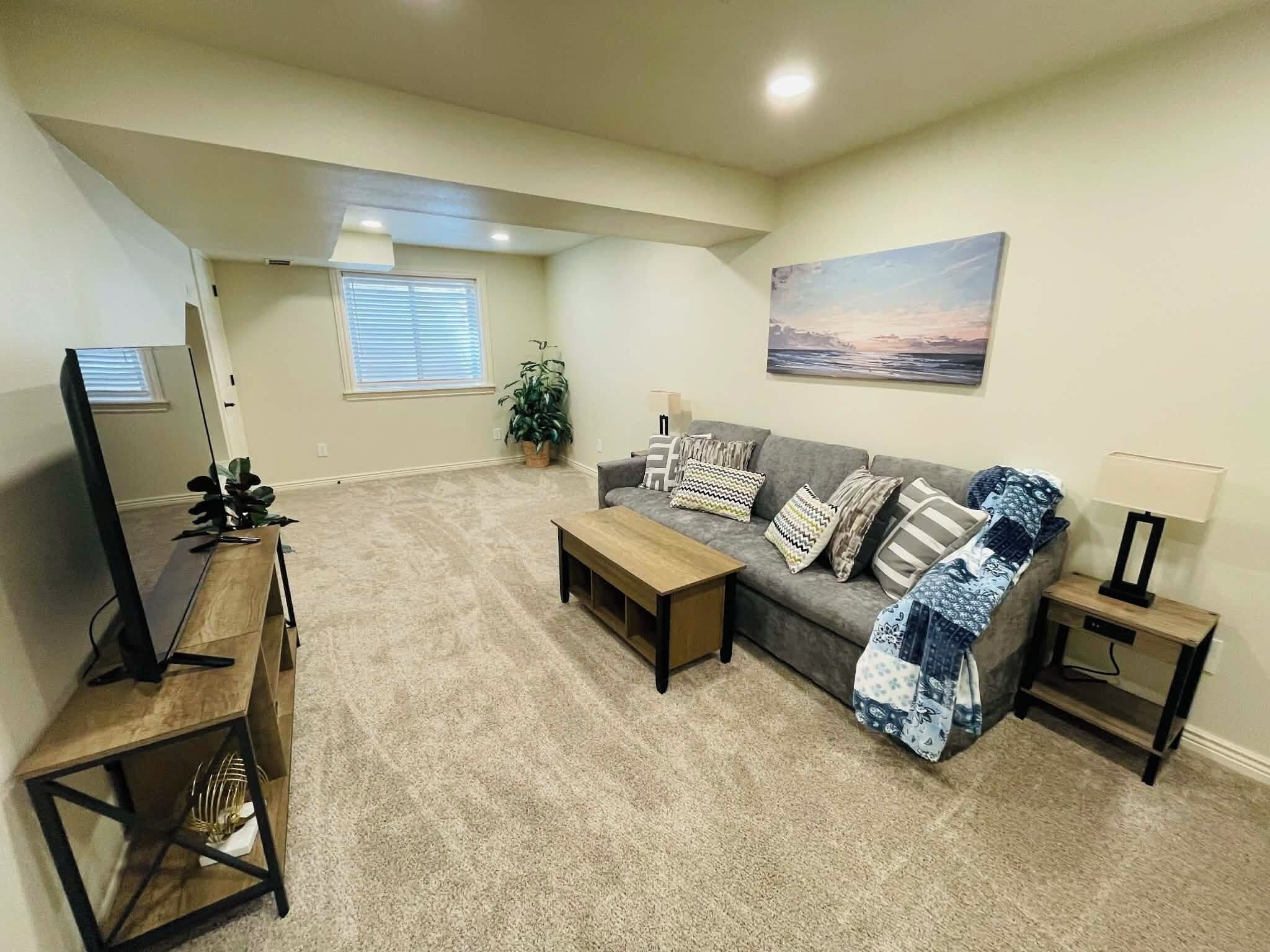 A living room with a grey sofa, wooden coffee table, and a TV stand.