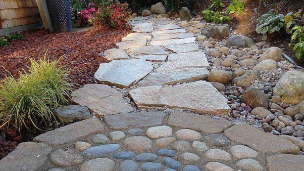 A stone pathway with a circular pattern of stones in the center, surrounded by larger stones and pebbles. - Quality Luxury Apartment With Killer View & Double Studio (Bellevue)