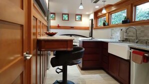 A narrow kitchen with wooden cabinets, a countertop, and a sink. There are windows above the sink and a ceiling light fixture. - Quality Luxury Apartment With Killer View & Double Studio (Bellevue)