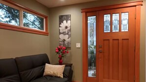 A living room with a dark-colored sofa, a vase of red flowers, and a large floral painting on the wall. - Quality Luxury Apartment With Killer View & Double Studio (Bellevue)