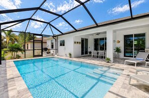 A covered swimming pool with a patio area, outdoor seating, and a view of the surrounding landscape. - Upscale Bonita Springs Villa • Heated Pool • Bikes • 5 Min Beach (Bonita Springs)