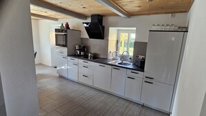 A modern kitchen with stainless steel appliances, a built-in oven, and a large refrigerator. - Simones-Ferienhaus.de Cozy vacation in North Friesland for up to 6 people. (Drage)