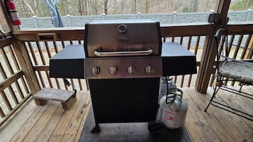Enjoy al fresco dining with a stainless steel grill and deck overlooking a wooded area.