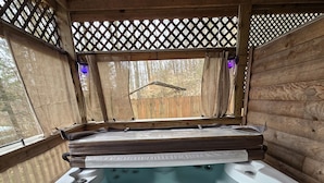 Een hottub met bedieningspaneel, omringd door houten wanden en een traliesraam.
