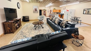 A living room with a TV, sofa, coffee table, and a fireplace. - HUGE Gameroom-Style Barndo in the countryside, minutes to Lake McMurtry & OSU! (Stillwater)