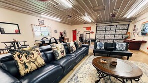 A modern living room with a black leather sofa, a round coffee table, and a patterned rug. - HUGE Gameroom-Style Barndo in the countryside, minutes to Lake McMurtry & OSU! (Stillwater)