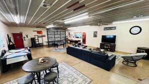 A spacious room with a pool table, a sofa, a television, and a clock on the wall. - HUGE Gameroom-Style Barndo in the countryside, minutes to Lake McMurtry & OSU! (Stillwater)