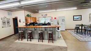 A kitchen with a bar area, wooden cabinets, a microwave, and a refrigerator. - HUGE Gameroom-Style Barndo in the countryside, minutes to Lake McMurtry & OSU! (Stillwater)