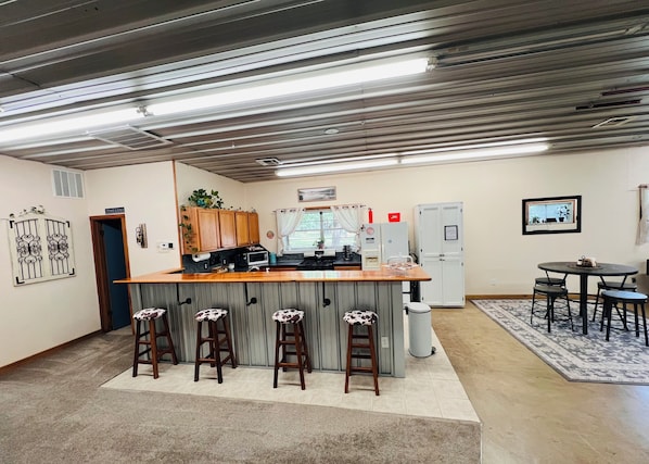 A kitchen with a bar area, wooden cabinets, a microwave, and a refrigerator.
