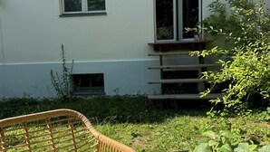 A wicker chair and table with a cup and a potted plant in front of a white building with windows. - Beautiful apartment in a quiet location with good connections to Potsdam and Berlin (Potsdam)
