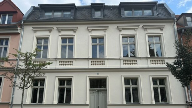 A two-story building with a symmetrical facade, a central entrance with a double door, and a brick base. - Beautiful apartment in a quiet location with good connections to Potsdam and Berlin (Potsdam)