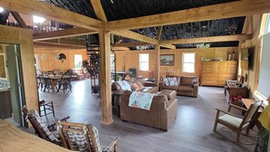 Amplia sala de estar con suelo de madera, sofás de cuero y un techo alto con vigas a la vista.