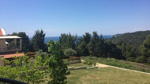 Il s’agit d’une propriété résidentielle offrant une vue sur la mer, dotée d’une pelouse bien entretenue et d’un bâtiment dont le toit est recouvert de tuiles rouges.
