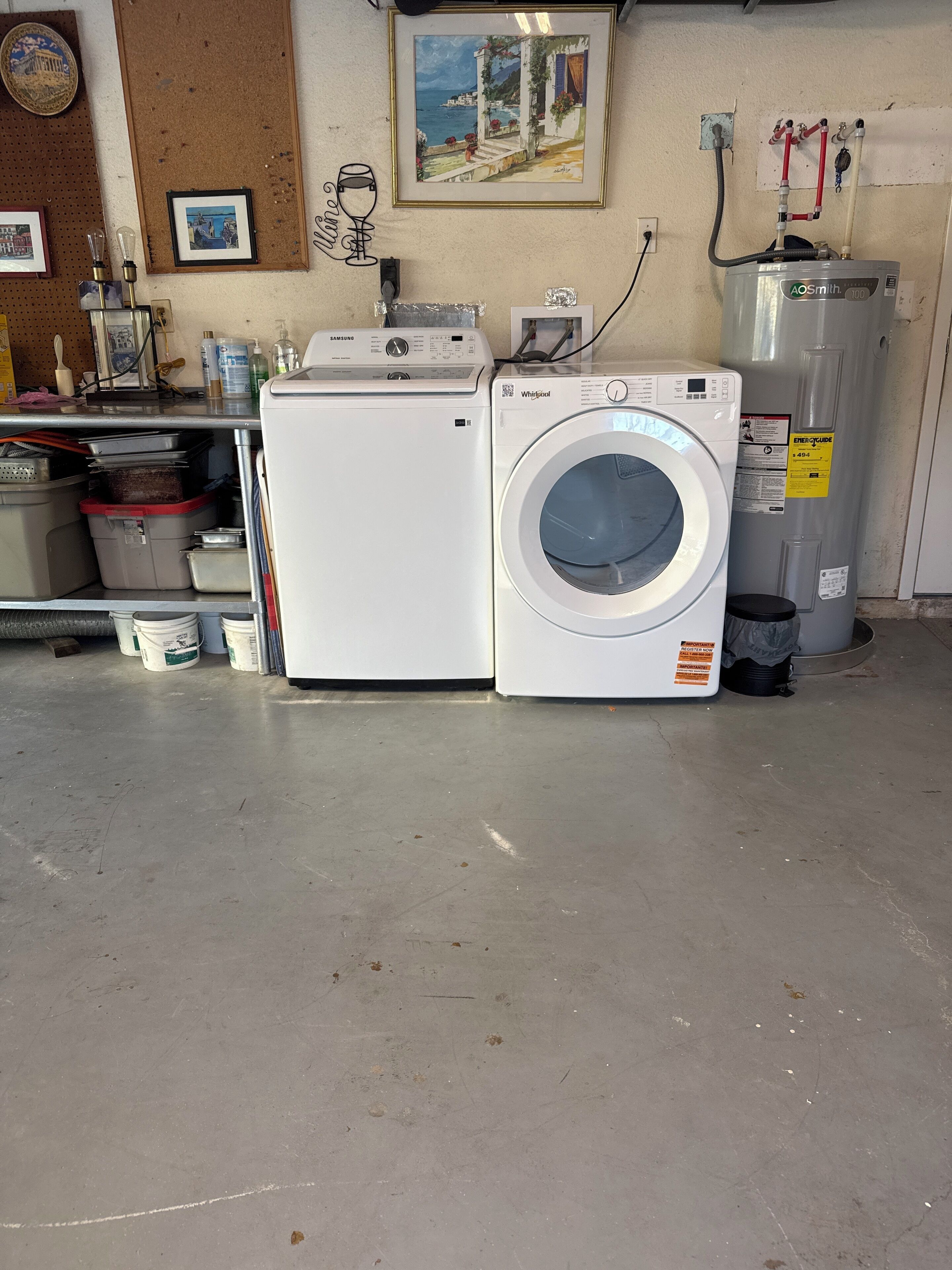 A laundry room with a Samsung washer and a Whirlpool dryer, a pegboard with various items, and a water heater on the wall.