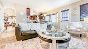 A living room with a leather sofa, a glass coffee table, and a white armchair. - Pine & Peak - Bright, Airy Home w/ Big Views in Peaceful Family Area (Colorado Springs)