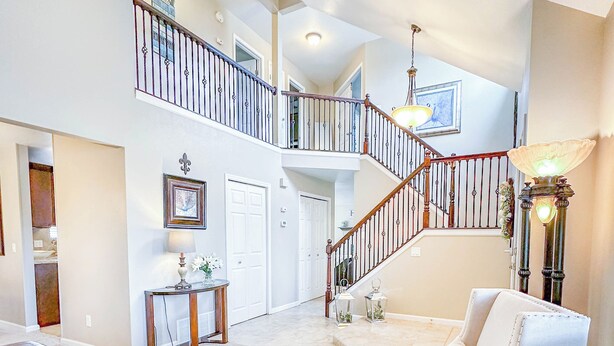 A spacious living area with a high ceiling, a staircase, and a chandelier. - Pine & Peak - Bright, Airy Home w/ Big Views in Peaceful Family Area (Colorado Springs)