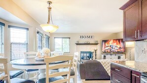 A kitchen with a dining area, a fireplace, and a 'HOME' sign on the wall. - Pine & Peak - Bright, Airy Home w/ Big Views in Peaceful Family Area (Colorado Springs)