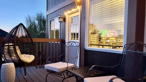 A deck with outdoor seating, a patterned rug, and string lights. - Pine & Peak - Bright, Airy Home w/ Big Views in Peaceful Family Area (Colorado Springs)