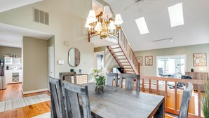 A spacious dining area with a wooden table and chairs, a chandelier, and a staircase leading to an upper level. - RVA Old Willow Bungalow | Quaint & Quiet | 2 Kings (Richmond)