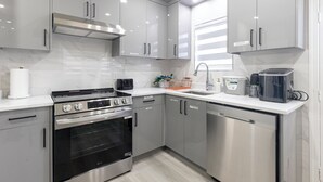A modern kitchen with stainless steel appliances, grey cabinetry, and a white countertop. - Vancouver Cozy Cove (Vancouver)
