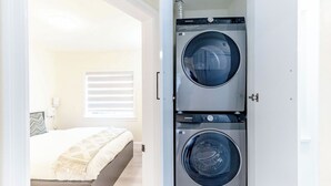 A compact laundry room with two stacked front-loading washing machines. - Vancouver Cozy Cove (Vancouver)