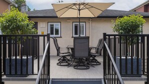 A staircase leading to a patio area with outdoor furniture and a large umbrella. - Vancouver Cozy Cove (Vancouver)