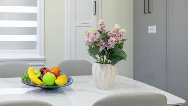 A dining table with a fruit bowl and a vase of flowers. - Vancouver Cozy Cove (Vancouver)