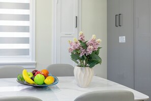 Une table à manger avec un panier de fruits et un vase de fleurs.