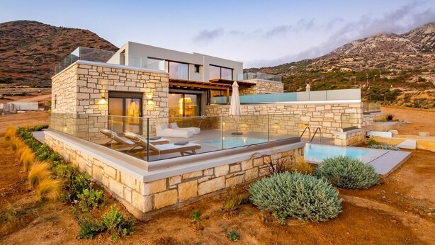 A modern house with a swimming pool, stone walls, and a view of the mountains. - Anemelia Villas (Karpathos)