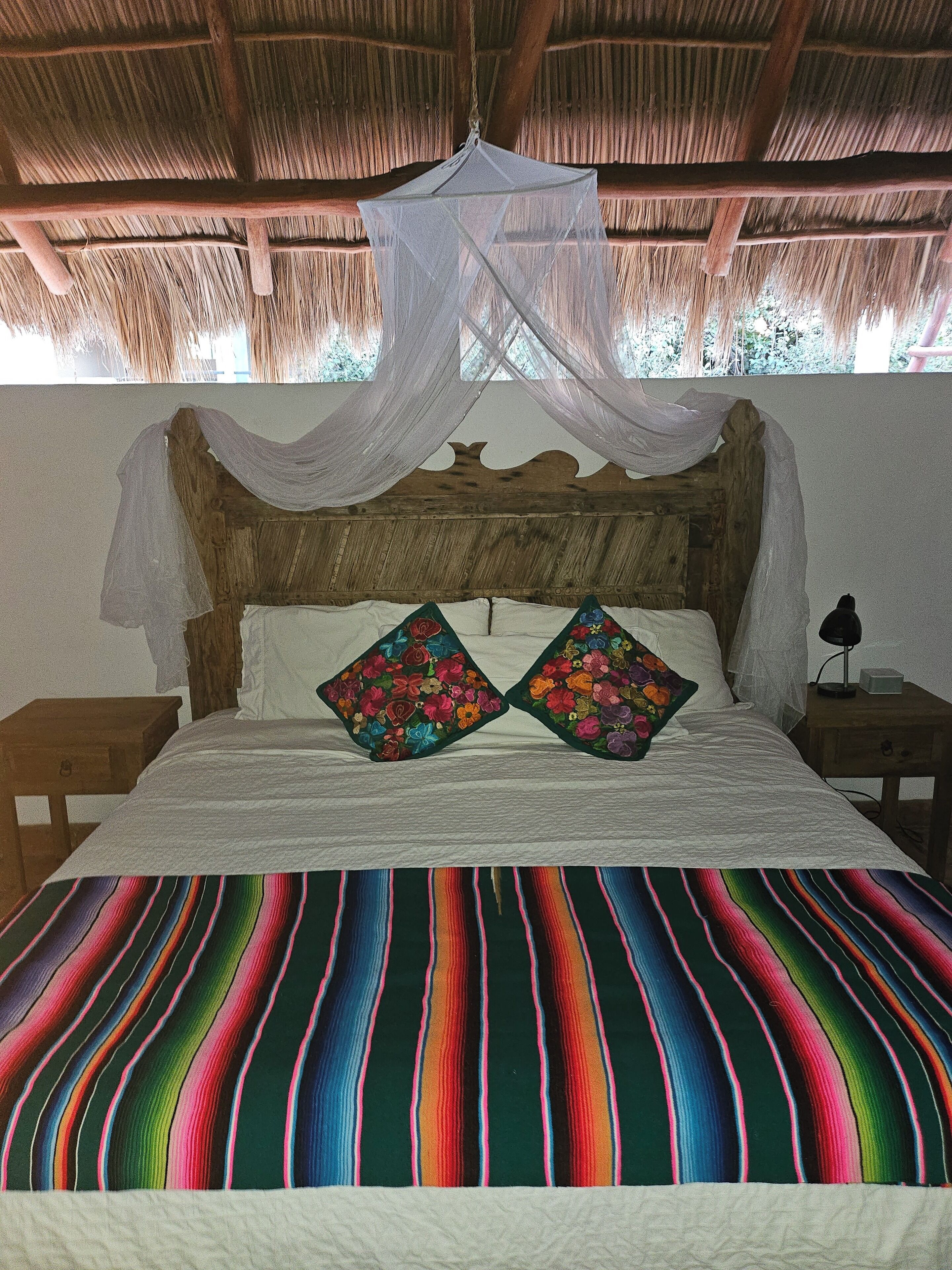 A bed with a colorful striped bedspread, a wooden headboard, and two floral pillows.