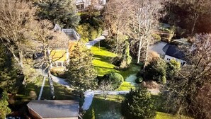 An aerial view of a residential area with houses, a green lawn, and a small pond. - Timeless Villa with Grand Garden near Brussels (Overijse)