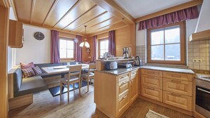 Een gezellige keuken met houten kastjes, een zithoek met een bank en een groot raam dat natuurlijk licht binnenlaat.