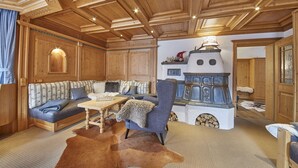 Een gezellige woonkamer met een houten plafond, een zithoek, een tafel en een decoratieve kachel.