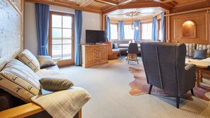 En mysig stuga med träpanel i taket, en soffa, ett matbord och en tv.