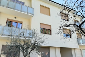 Ein mehrstöckiges Gebäude mit Balkonen, Fenstern und einem Baum im Vordergrund.