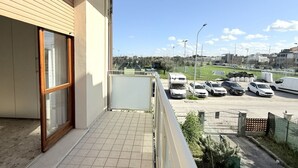 Un balcón con vista a un estacionamiento y un campo deportivo.