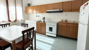 Una cocina con armarios de madera, una estufa blanca y una mesa de comedor con sillas.