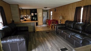Amplia sala de estar con cocina, una mesa de comedor y dos sofás de cuero.