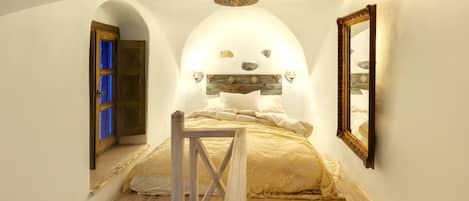 A bedroom with a wooden bed, a mirror, and a unique arched ceiling.