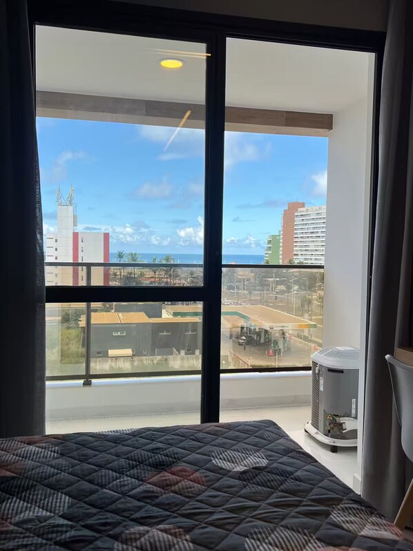 Un dormitorio con un ventanal que ofrece vistas a un paisaje urbano y una masa de agua.
