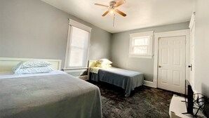 A bedroom with two beds, a ceiling fan, a window, and a door. - Spacious 4-bedroom house with AC, WiFi in  Mansfield (Mansfield)