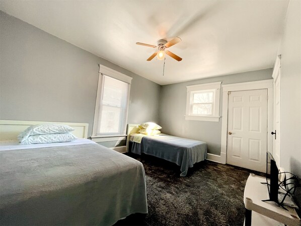 A bedroom with two beds, a ceiling fan, a window, and a door. - Spacious 4-bedroom house with AC, WiFi in  Mansfield (Mansfield)