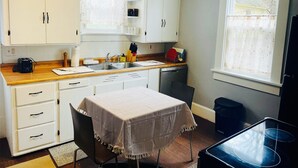 A compact kitchen with white cabinets, a wooden countertop, a sink, and a table with a tablecloth. - Spacious 4-bedroom house with AC, WiFi in  Mansfield (Mansfield)