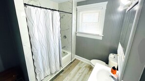 A bathroom with a shower, a toilet, a sink, and a window with blinds. - Spacious 4-bedroom house with AC, WiFi in  Mansfield (Mansfield)