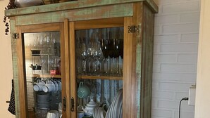 A wooden cabinet with glass doors containing various dishes and glassware. - St. Andrew House 3 (Centro Gramado)