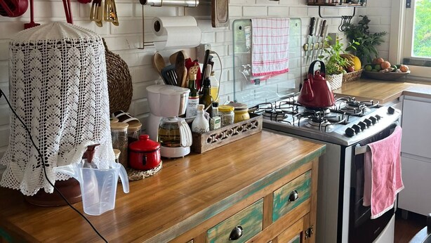 A kitchen with white brick walls, wooden cabinets, and a gas stove. - St. Andrew House 3 (Centro Gramado)