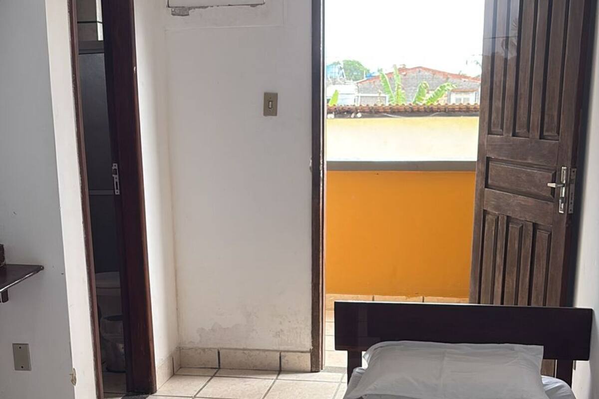 A bedroom with two beds, a window, an air conditioning unit, and a view of the outside.