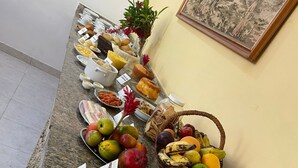 Una mesa de buffet con diversas frutas, pasteles y una jarra de leche.